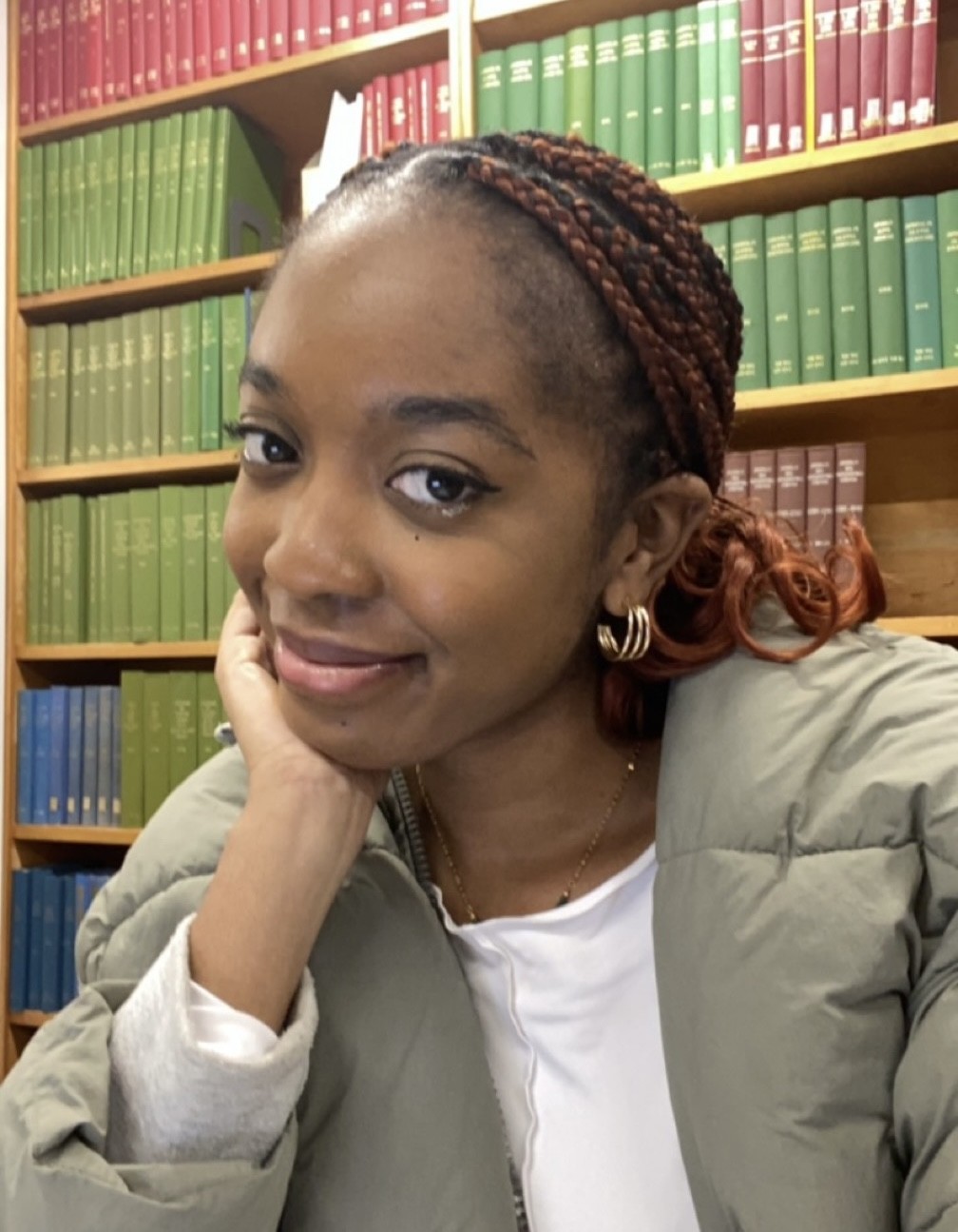 Chi looking into the camera with book cases behind