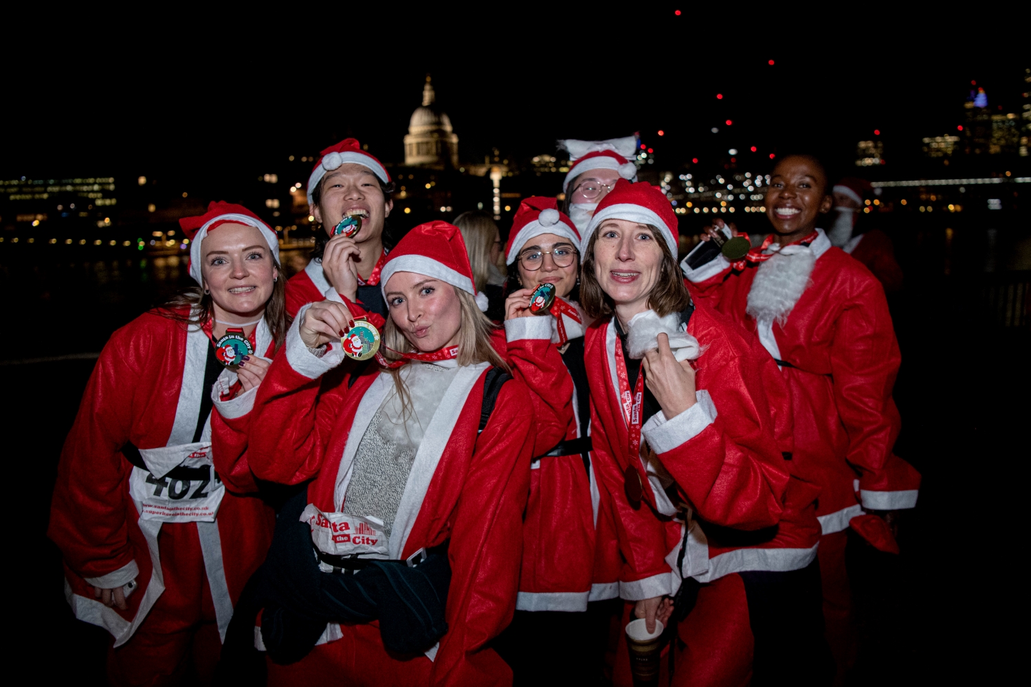 People holding their medals up after doing the Santa Run in the City running events