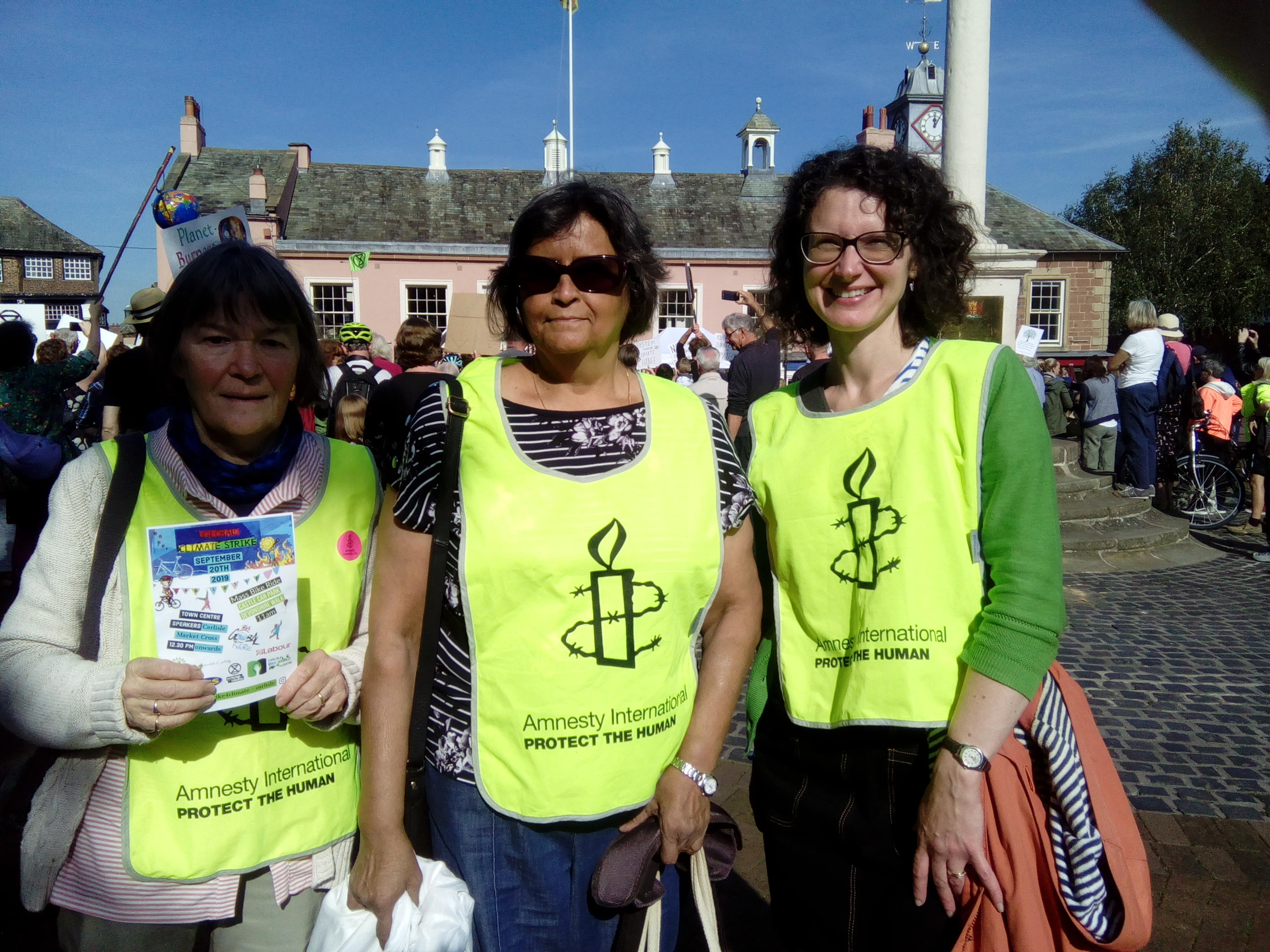 Three females wearing yellow Amnesty Tabbards