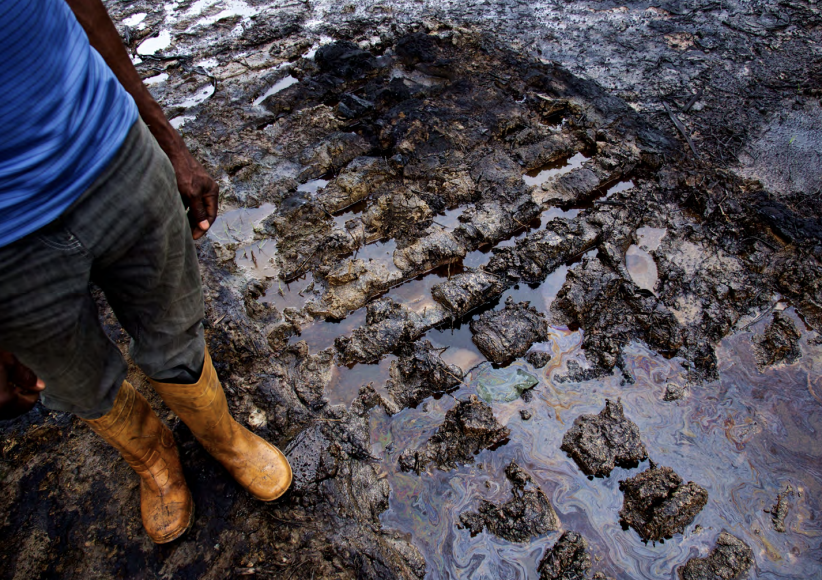 Person stands next to unremediated oil spill at Kegbara-Dere (K-Dere) community in Rivers State, Niger Delta, Nigeria, 2015.