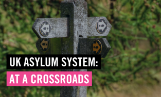 Image shows signs pointing in different directions and text overlay reads: UK asylum system at a crossroads