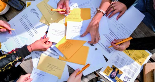 A photo of lots of people's hands holding pens over some paper