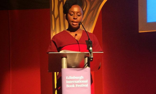 The picture shows an author standing at a podium speaking.