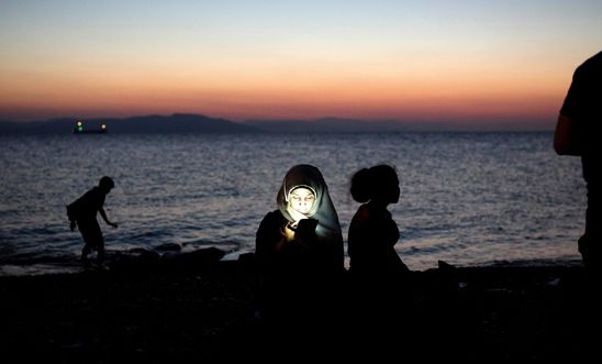 A migrant woman checking her phone after crossing the sea between Turkey and Greece