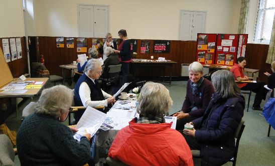 People sitting around tables writing cards