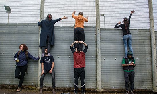 Protesters standing on each others shoulders to look inside the detention centre and talk to the people inside