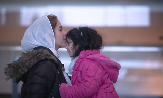 Woman kisses forehead of child