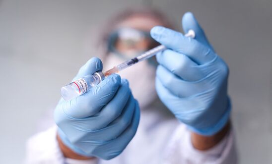 Clinician holds syringe and vial of vaccine