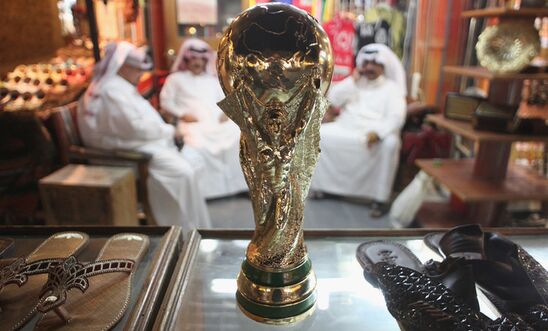 Arab men sit at a shoemaker's stall with a replica of the FIFA World Cup trophy in the Souq Waqif traditional market 