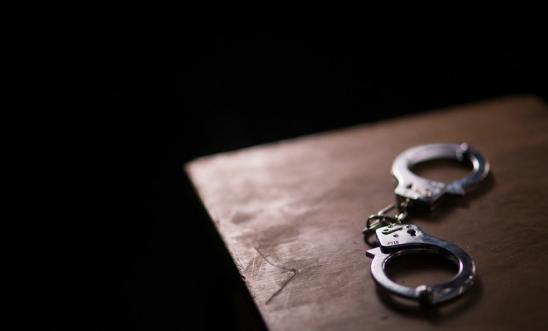 Handcuffs lie on a table with a black background