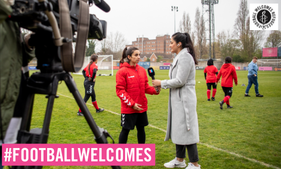 Sabreyah stands on a football pitch and is interviewed while being filmed