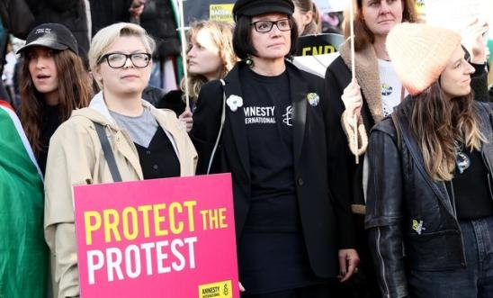 A number of people holding a sign saying 'Protect The Protest'