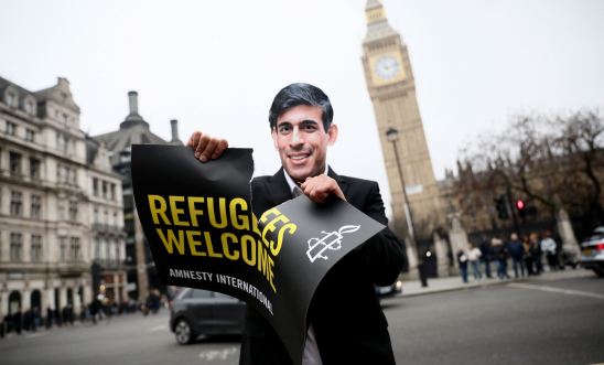 Rishi Sunak look-a-like ripping Refugee Welcome sign