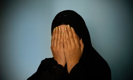 Woman in hijab holds her head in her hands with painted nails