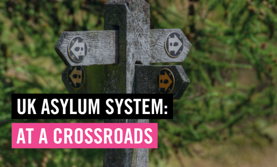 Image shows signs pointing in different directions and text overlay reads: UK asylum system at a crossroads