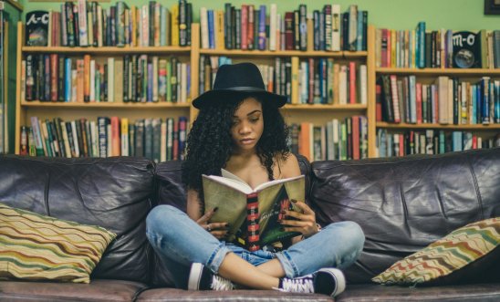 A woman sits cross-legged surrounded by books