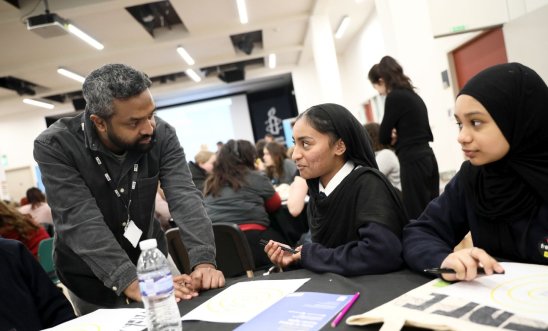 One adult talking to two school students