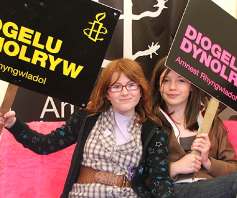 Two children holding Amnest human rights placards in the Welsh language 